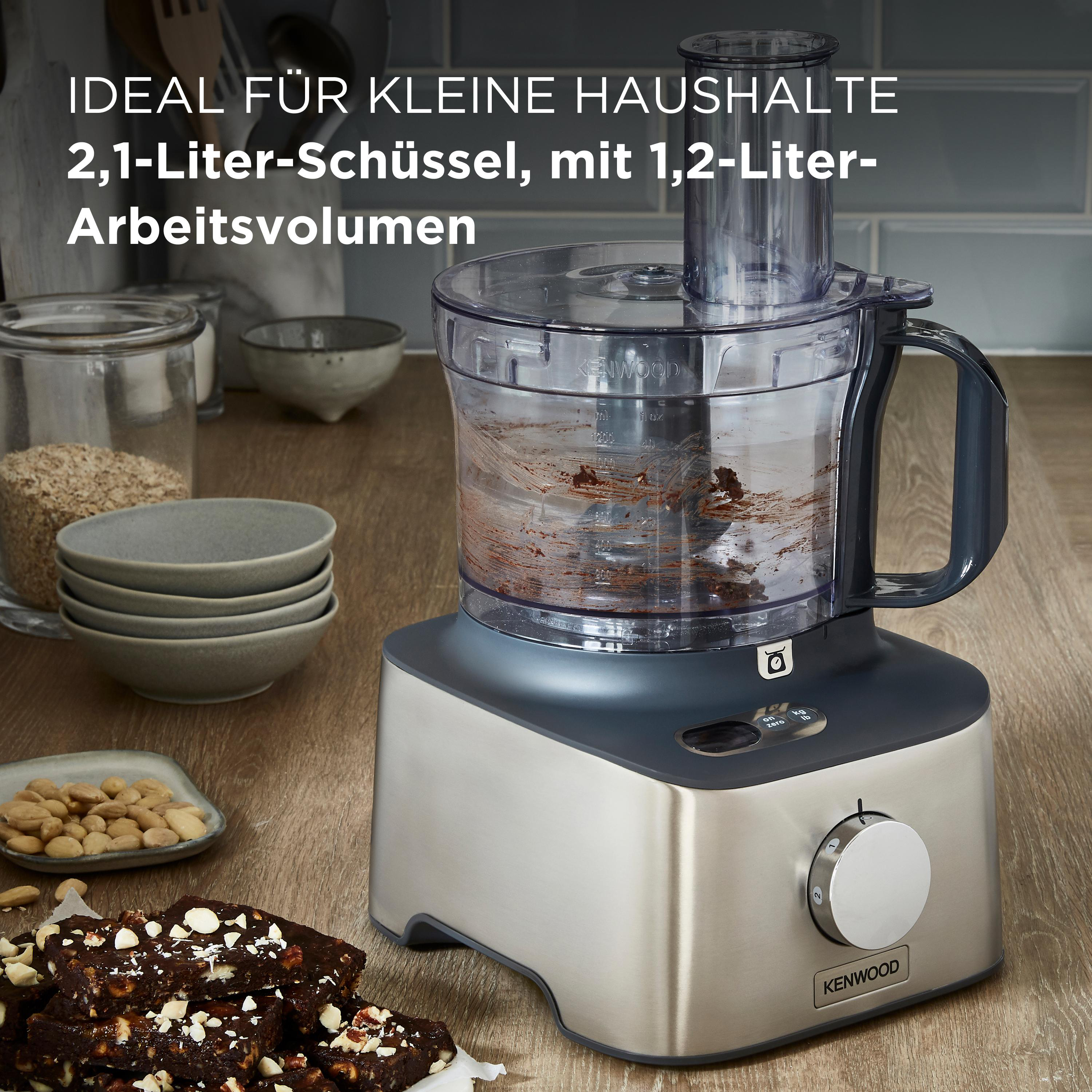 Ein Kenwood-Küchenroboter mit Edelstahlbasis. Zutaten befinden sich in der Schüssel und auf der Theke.