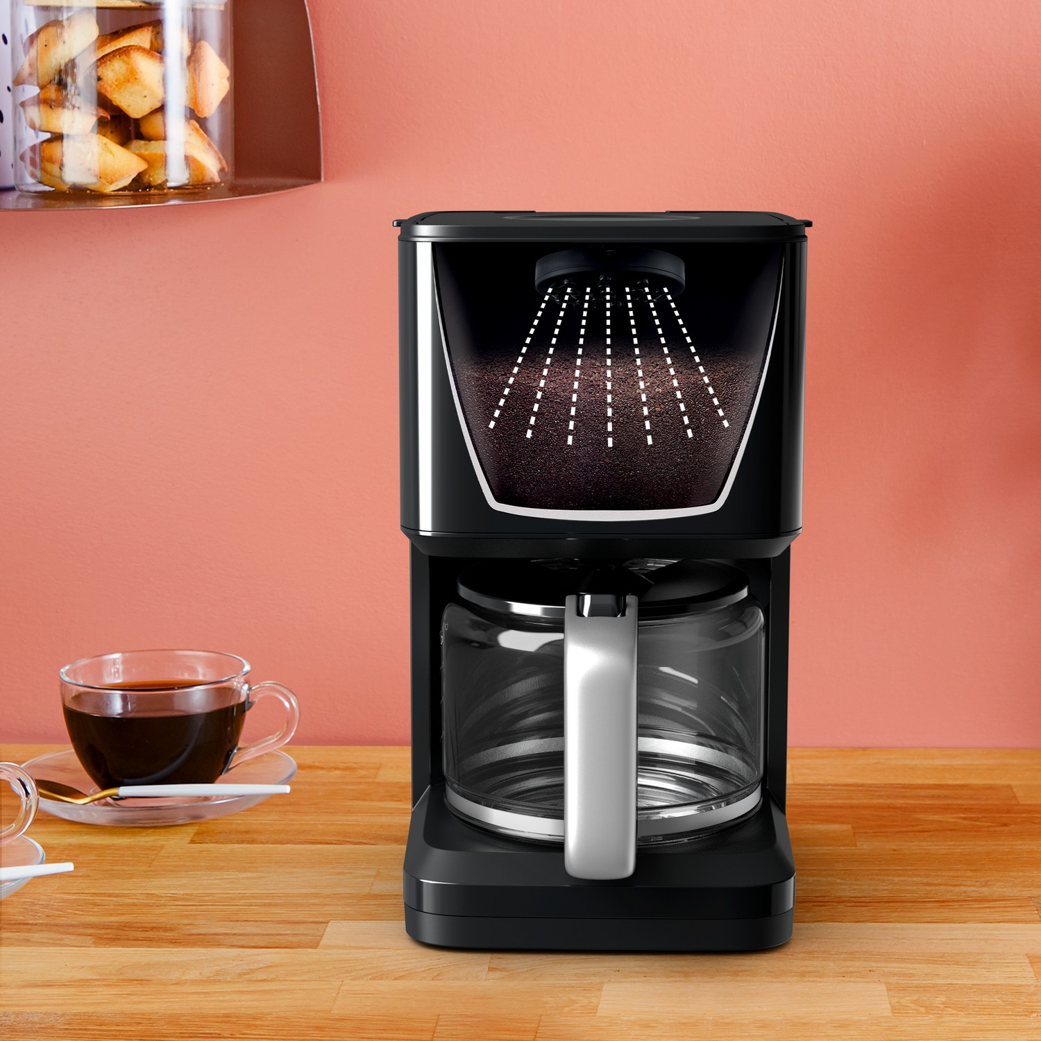 Een zwarte koffiezetapparaat met een glazen kan en koffie, met een houten tafel en perzikmuur.