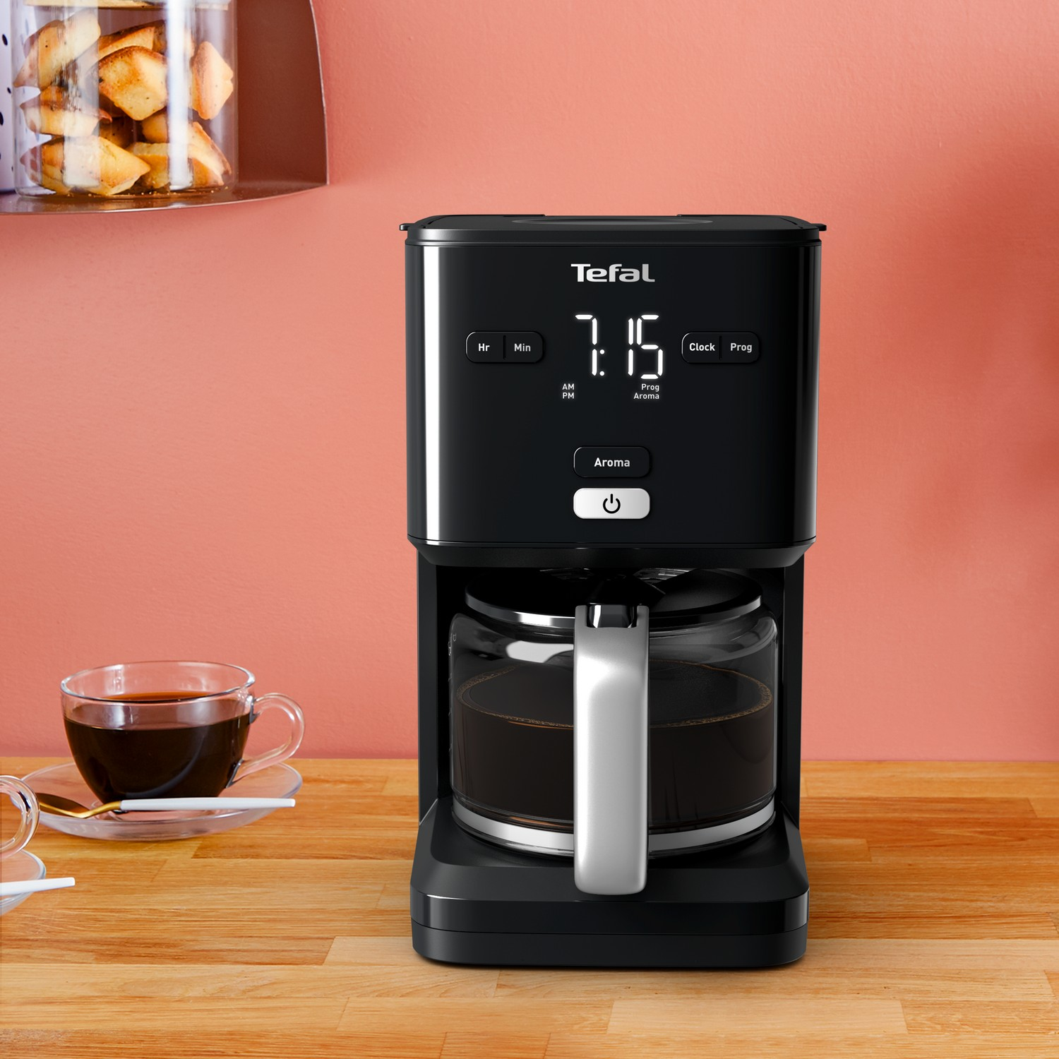 Zwart koffiezetapparaat met digitaal display, glazen kan en koffiekopje.