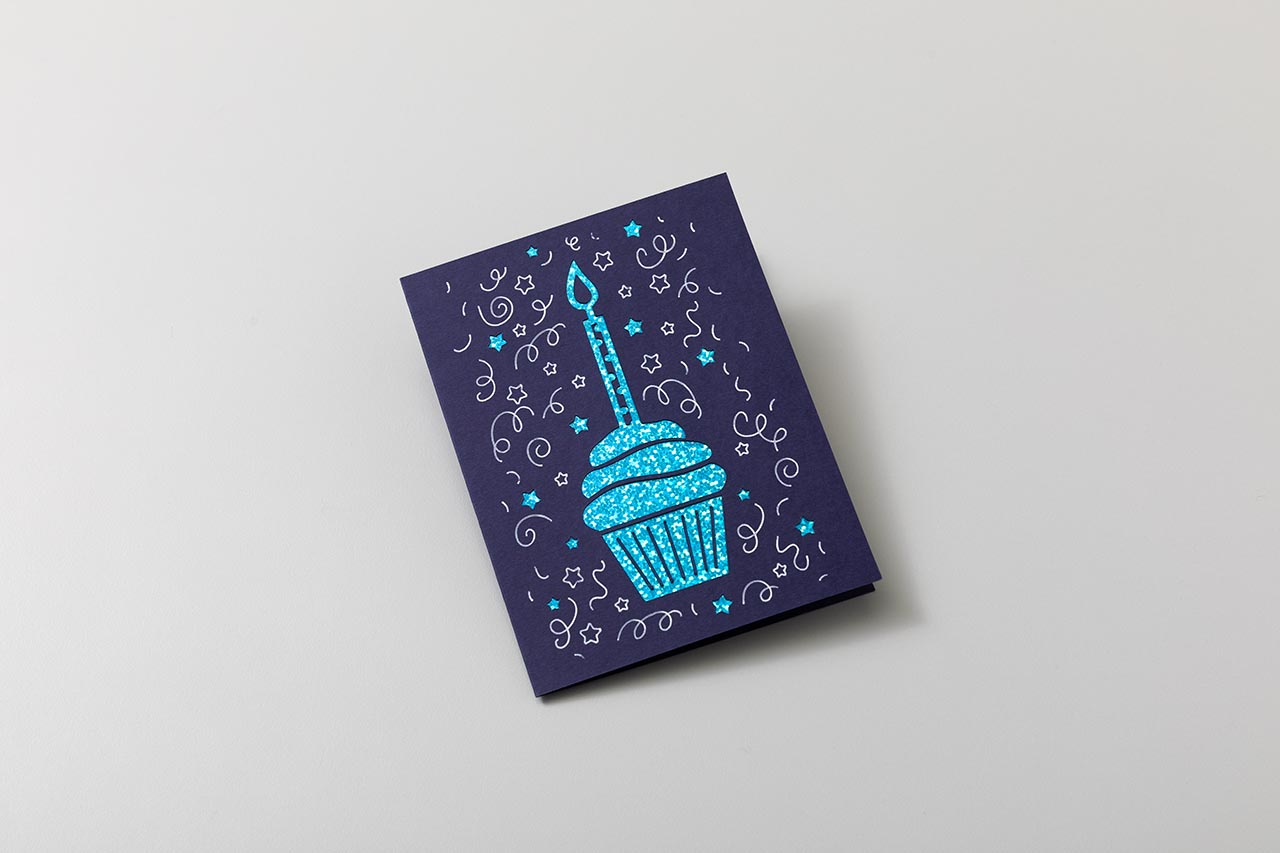 Eine dunkelblaue Geburtstagskarte mit Cupcake-Design und weißen Wirbeln.