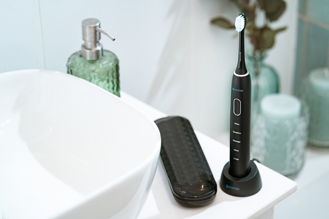 Czarna elektryczna szczoteczka do zębów na białej powierzchni. Ustawienia łazienkowe.