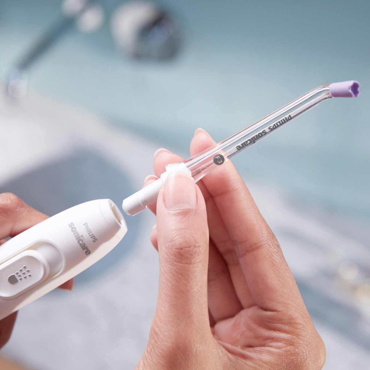 Osoba mocuje końcówkę irygatora Philips Sonicare do uchwytu.