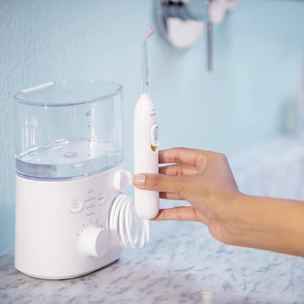 Biały irygator do jamy ustnej z dłonią trzymającą narzędzie.