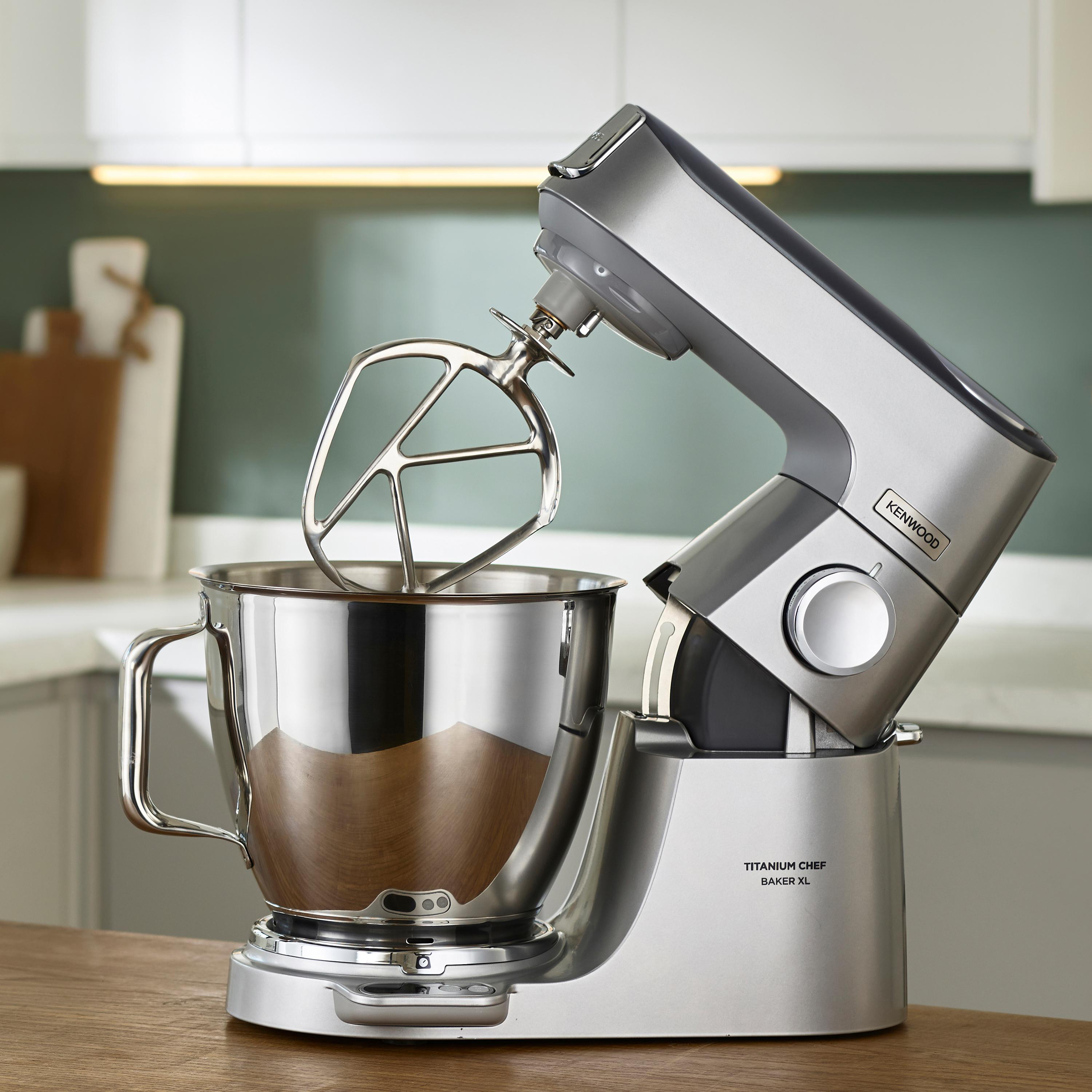 Silberner Küchenmixer mit Schüssel und Rührwerk, auf Holzoberfläche.