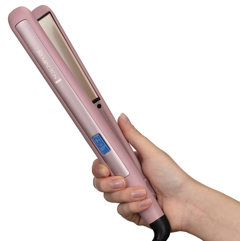 Dłoń trzymająca różową prostownicę do włosów z cyfrowym wyświetlaczem, czarnym kablem i logo Remington.