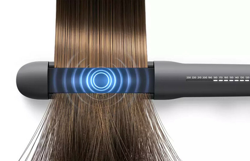 Prostownica do włosów z pasmami włosów między płytkami, pokazująca niebieskie światło.