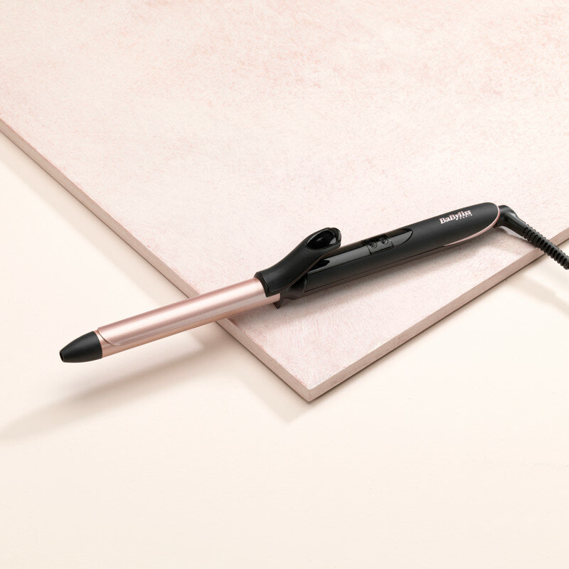 Lokówka, czarny uchwyt, złota lufa, na różowej i białej powierzchni.