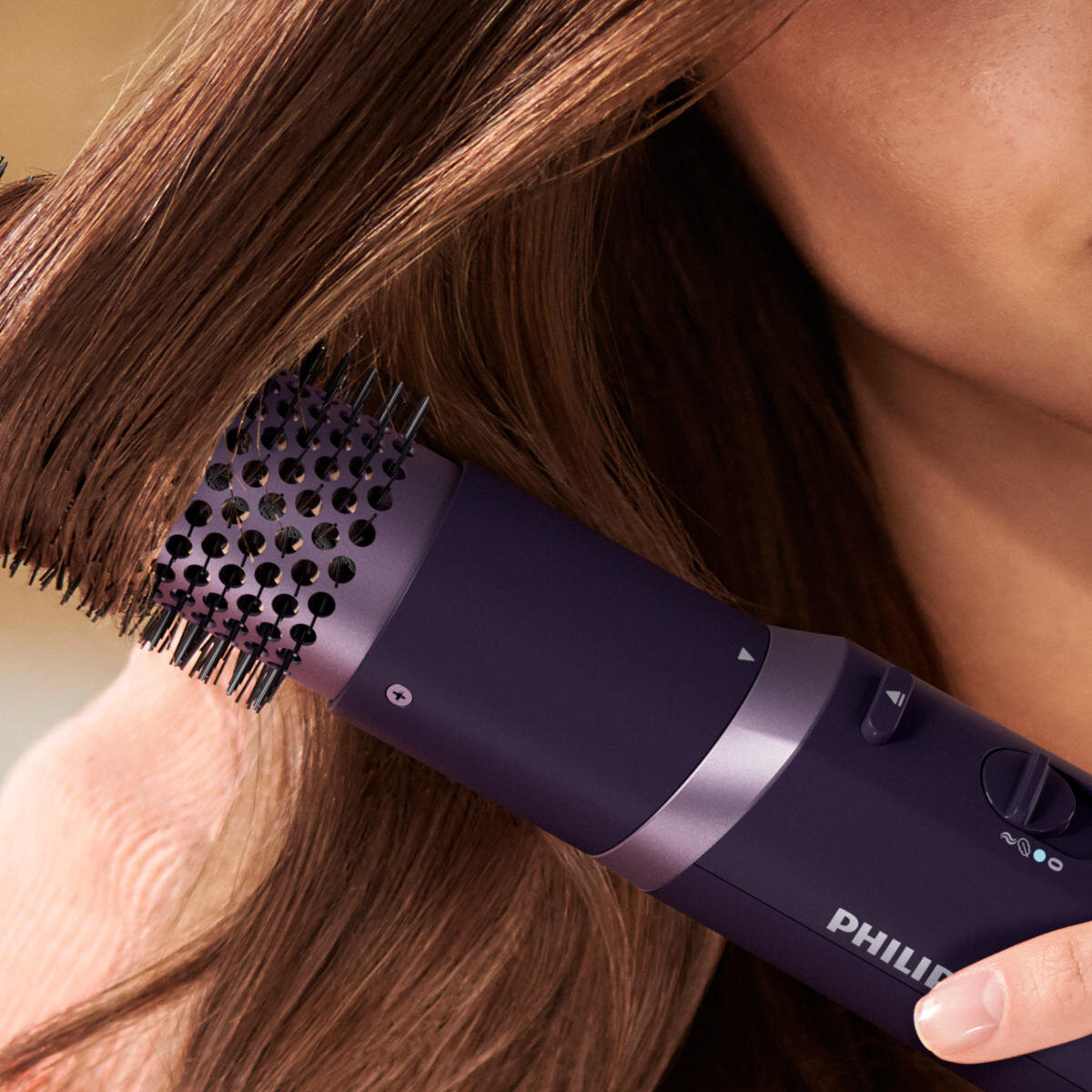 Kobieta używająca fioletowej szczotki do stylizacji włosów na brązowych włosach.