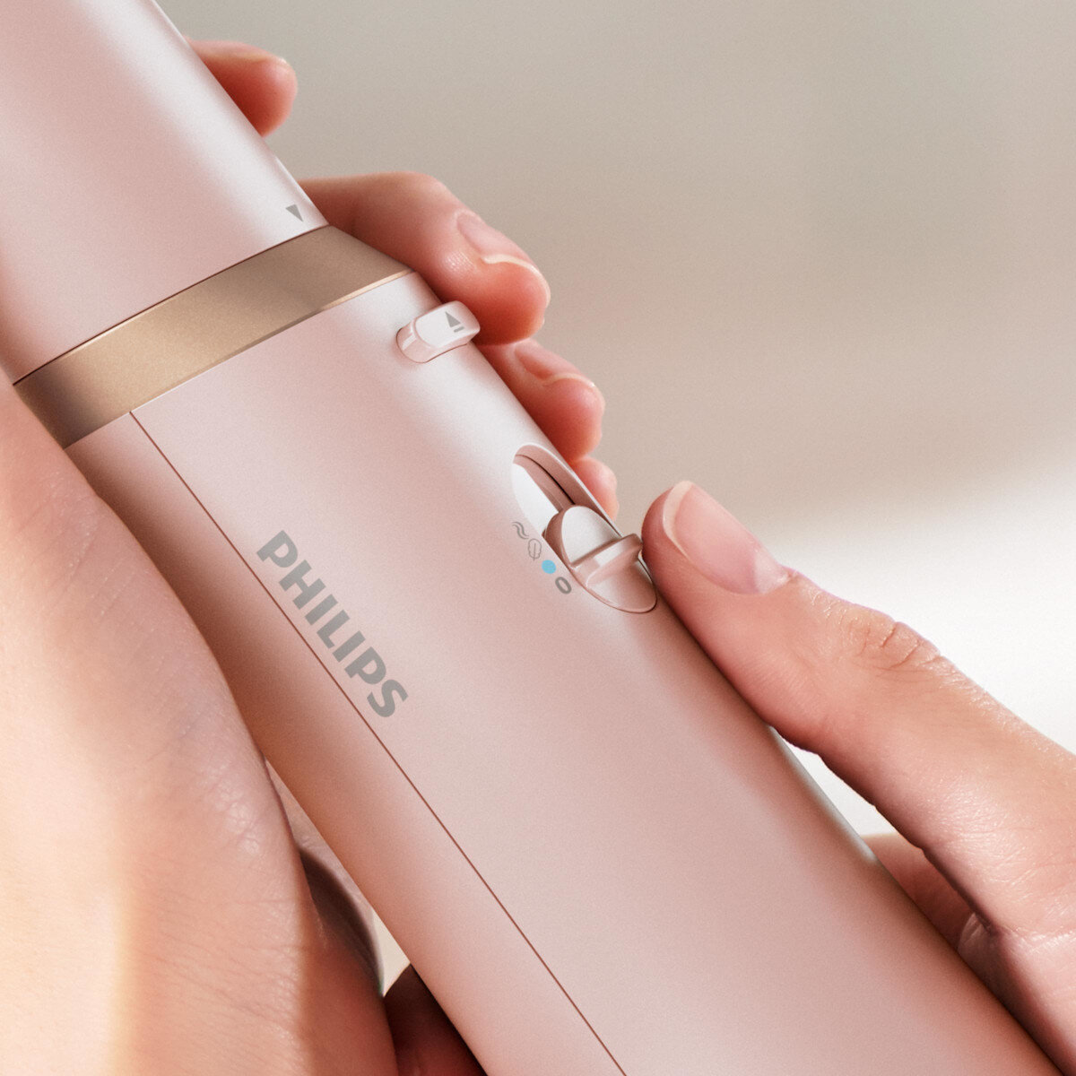 Dłoń regulująca różową lokówkę Philips, zbliżenie.