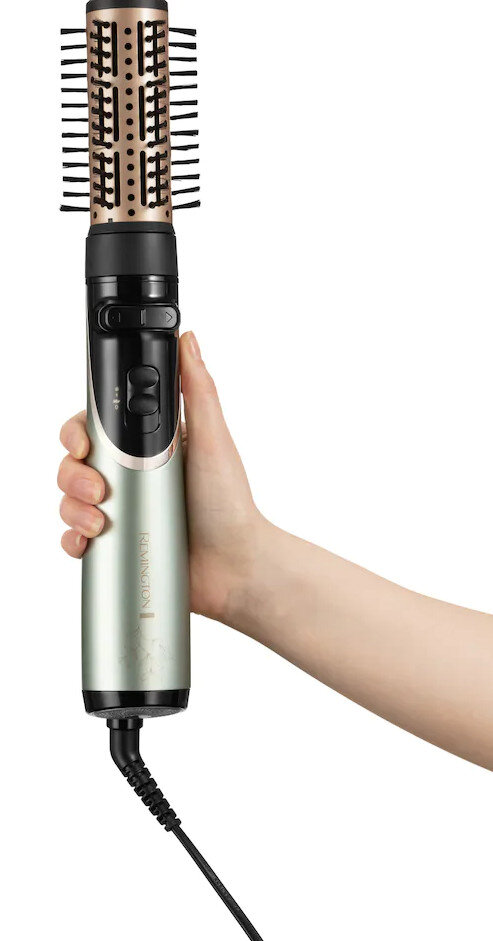 Dłoń trzymająca zielono-srebrne narzędzie do stylizacji włosów.