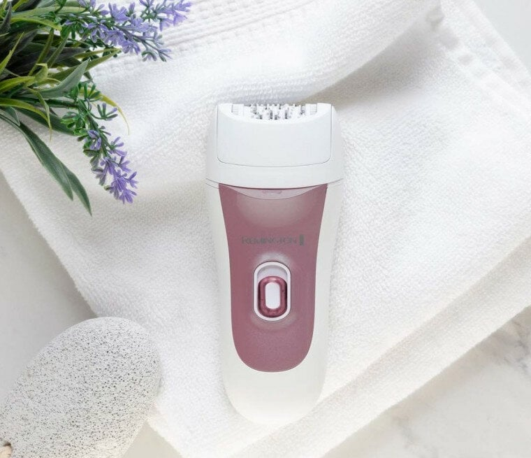 Biały i różowy depilator na białym ręczniku, z kamieniem i kwiatami lawendy.