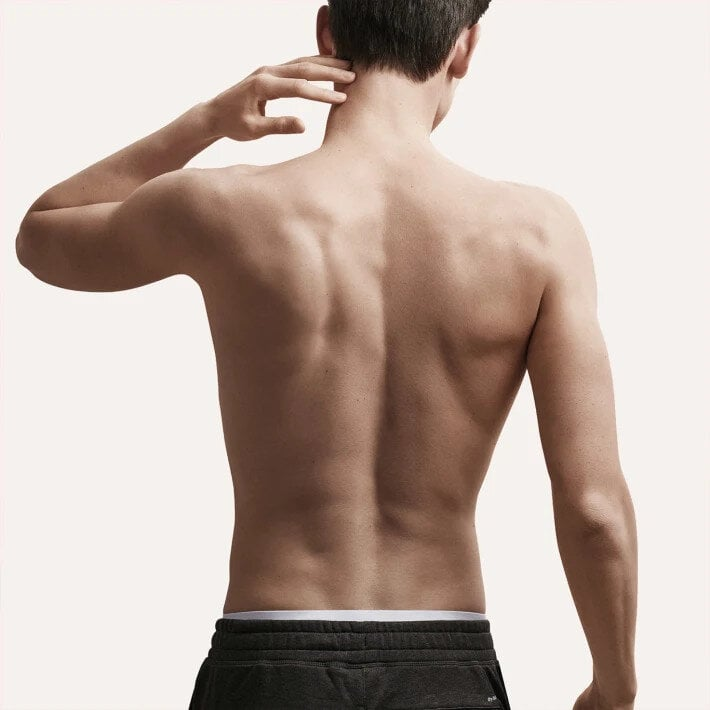 Plecy i ramiona mężczyzny. Jasna skóra i czarne szorty.