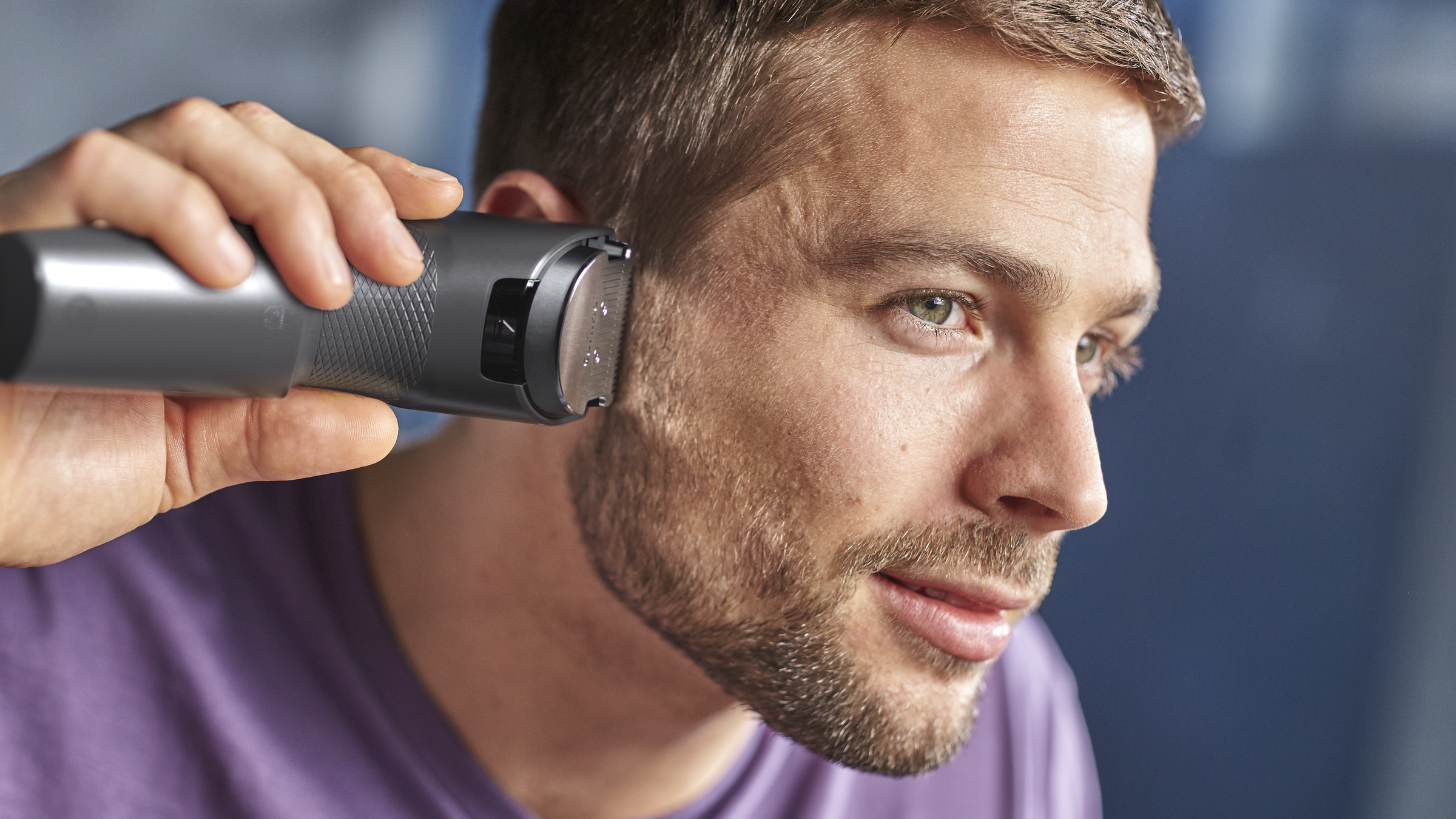 Mężczyzna przycinający brodę srebrno-szarą maszynką, zbliżenie.