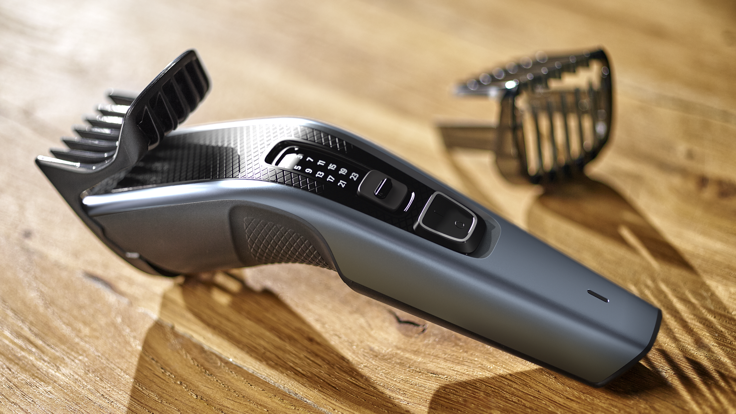 Maszynka do strzyżenia włosów na drewnianym stole, z regulacją ostrza i nasadką.