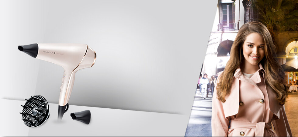 Suszarka do włosów, dyfuzor i dysza na białej powierzchni, kobieta w różowym płaszczu w tle.