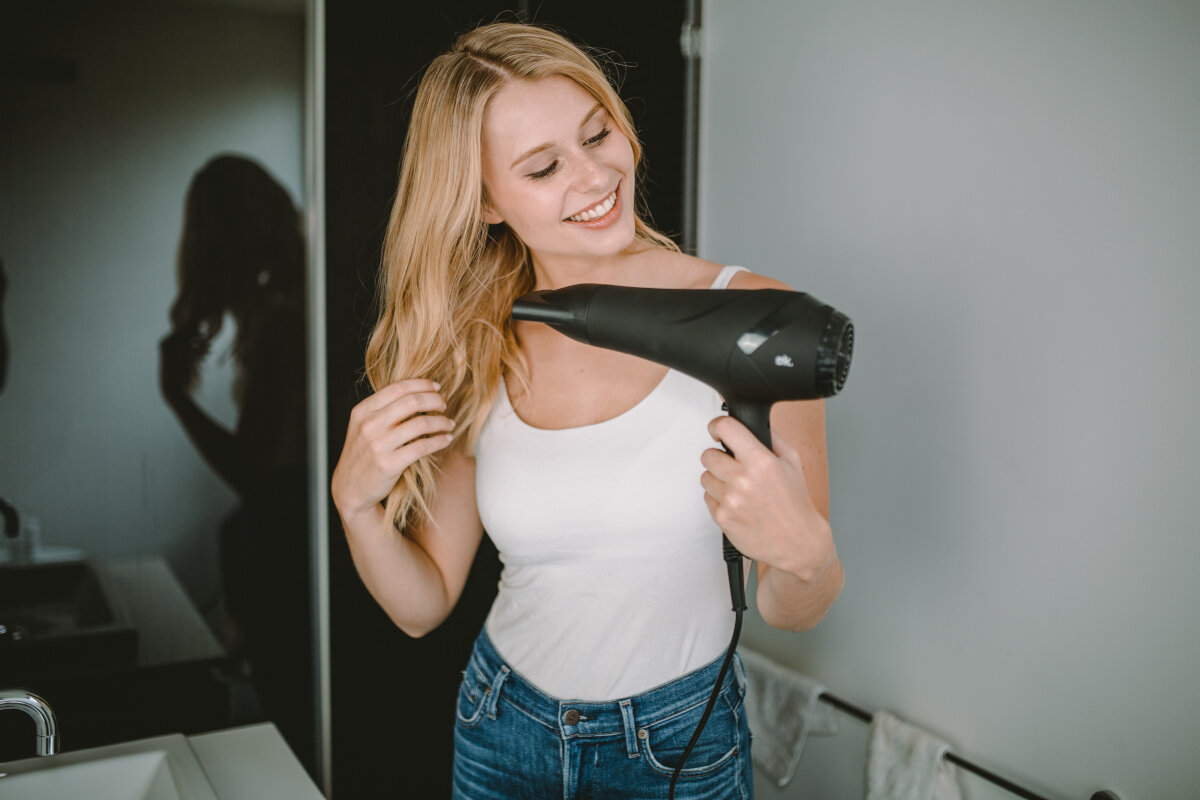 Suszarka do włosów na białej powierzchni. Czarna ze złotymi akcentami. Widoczny kabel.