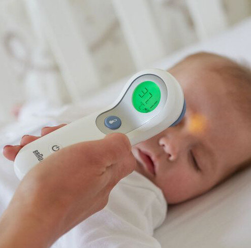 Czoło dziecka skanowane termometrem Braun. Wyświetlacz pokazuje 37.2.