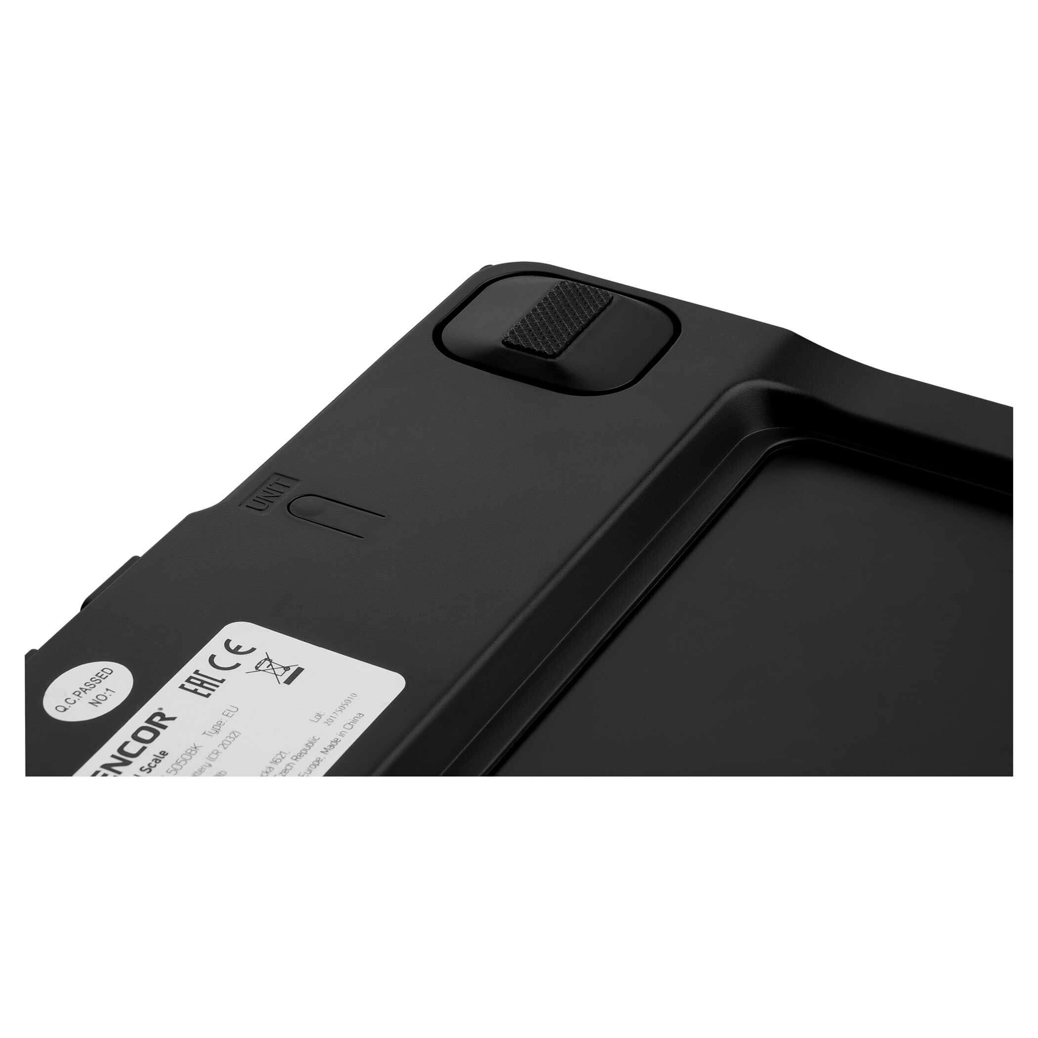 Czarna waga cyfrowa. Widok z góry. Biała naklejka ze szczegółami. Gumowy przycisk. Czarna powierzchnia.