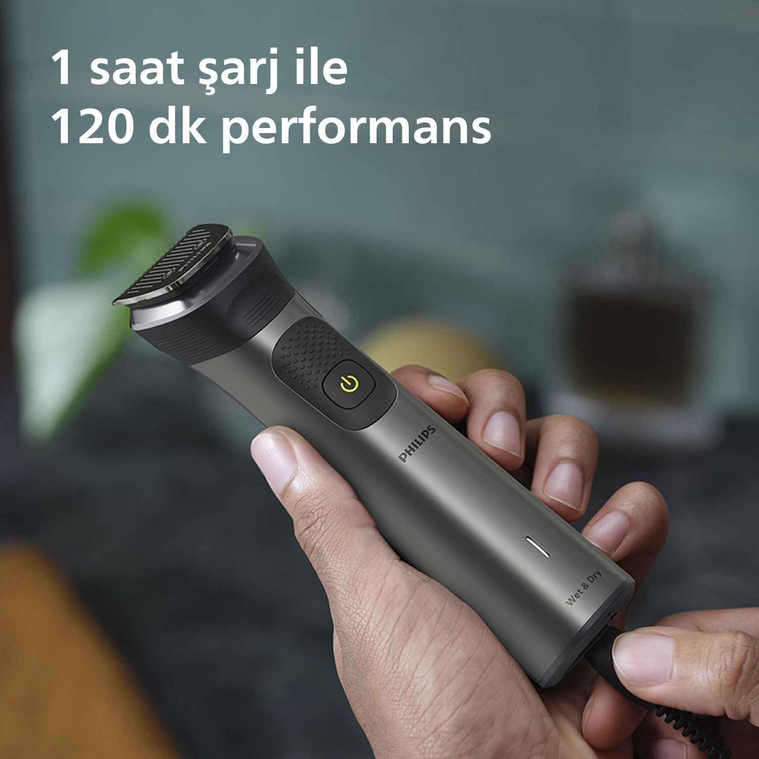 Bir adam, şarj kablosuyla gri bir Philips tıraş makinesi tutuyor. Metin: 120 dk performans için 1 saat şarj.