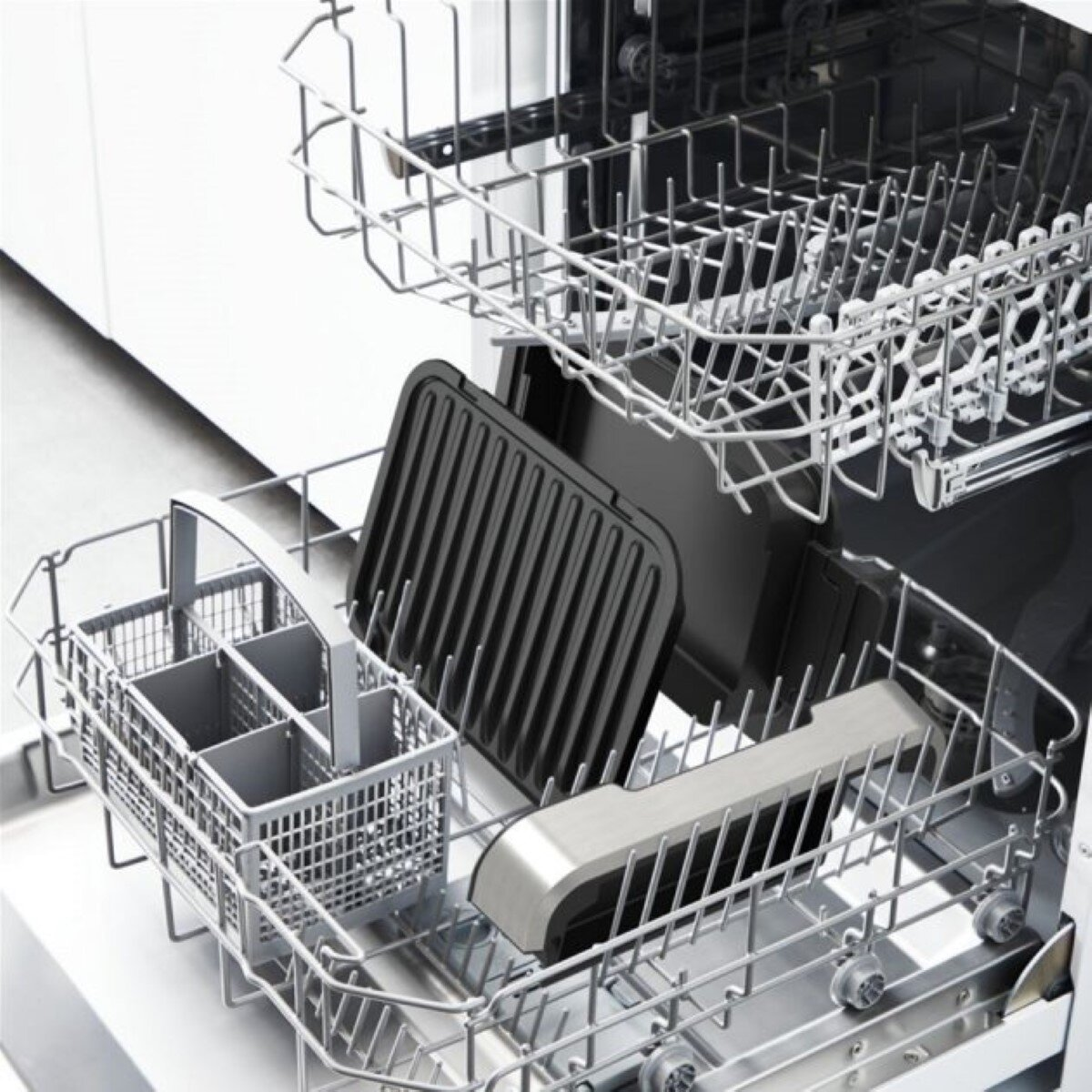 Wnętrze zmywarki z półkami i naczyniami. Zawiera patelnię grillową i kosz na sztućce.