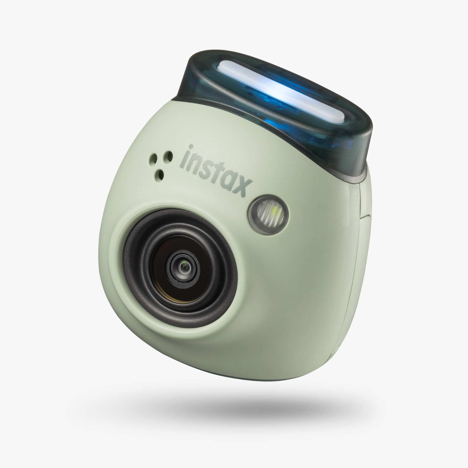 Bir lens ve flaşlı yeşil bir Instax anında fotoğraf makinesi. Kamera hafif açılı.