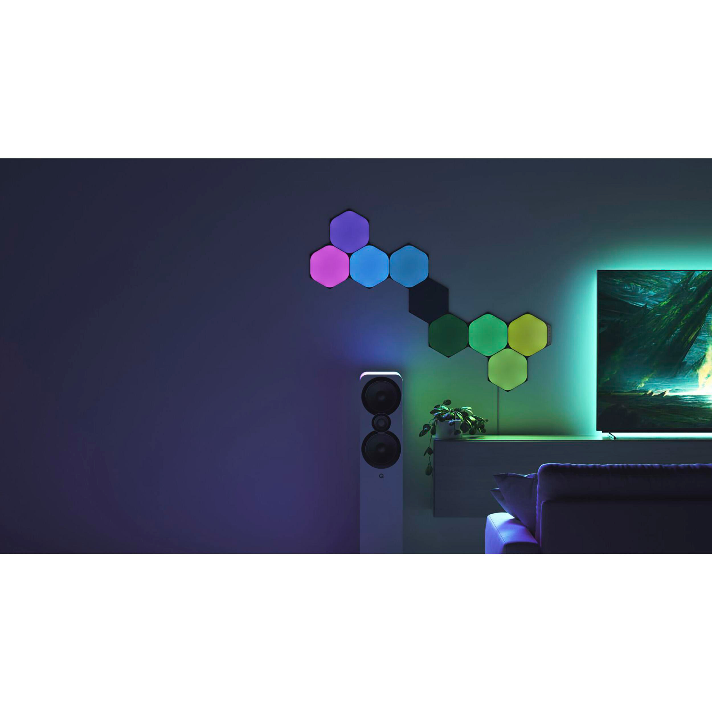 Sechseckige Lichter an einer Wand. Ein Lautsprecher und ein Fernseher sind auch im Raum.