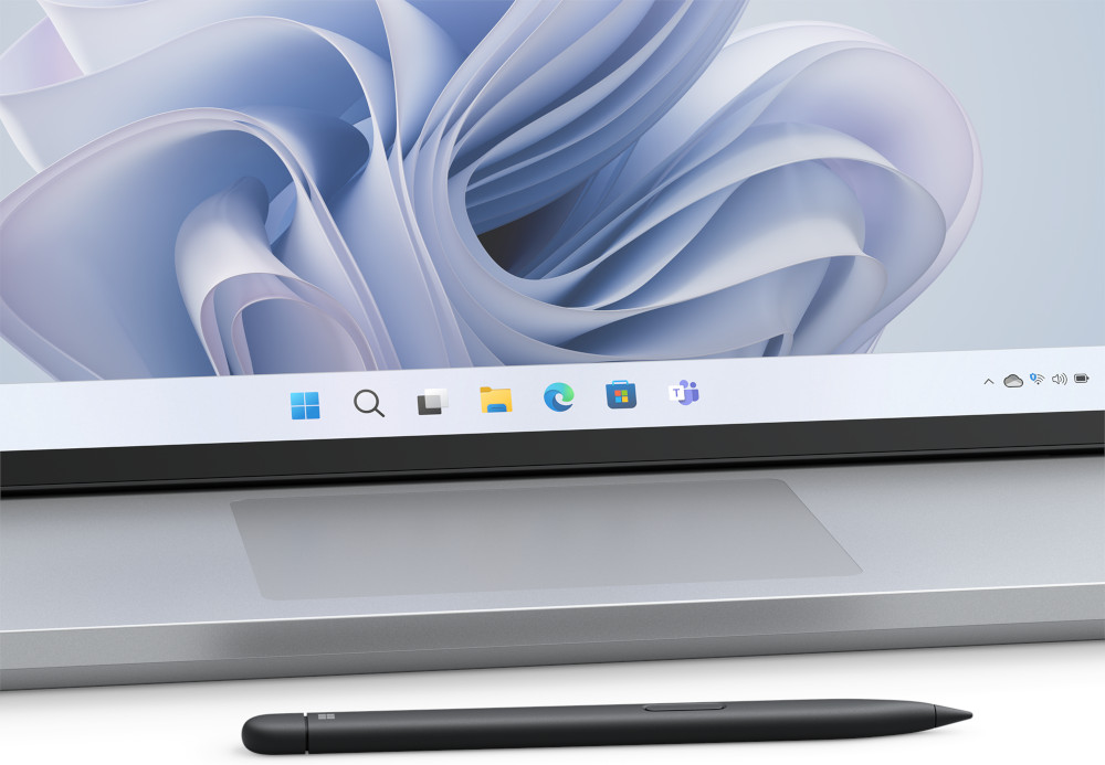 Close-up van een laptopscherm. Toont een taakbalk met pictogrammen en een stylus aan de onderkant.