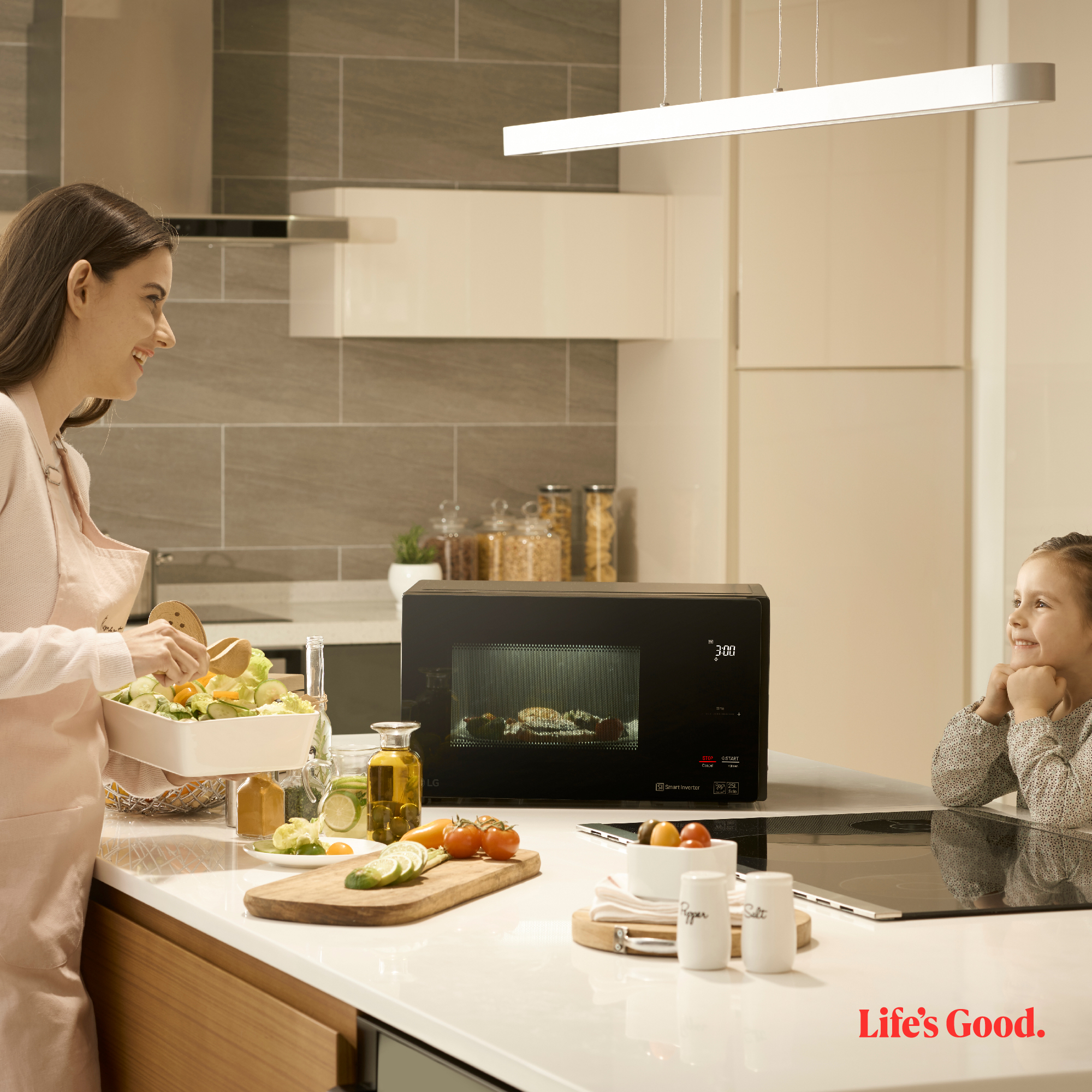 Una mujer y una niña en la cocina con un microondas.