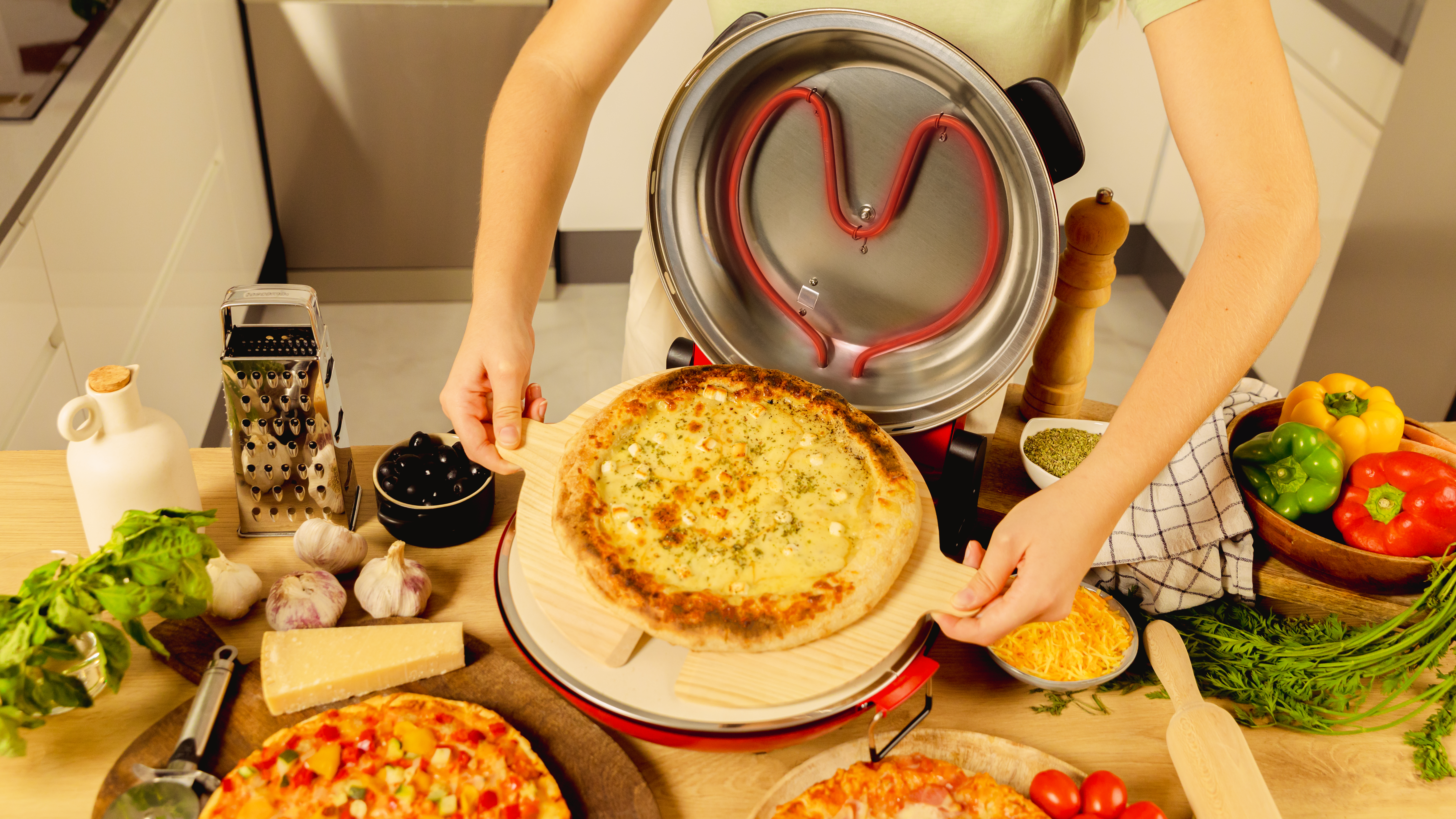 Una persona presenta una pizza en una tabla de madera desde un horno de pizza. Otras pizzas en la mesa.