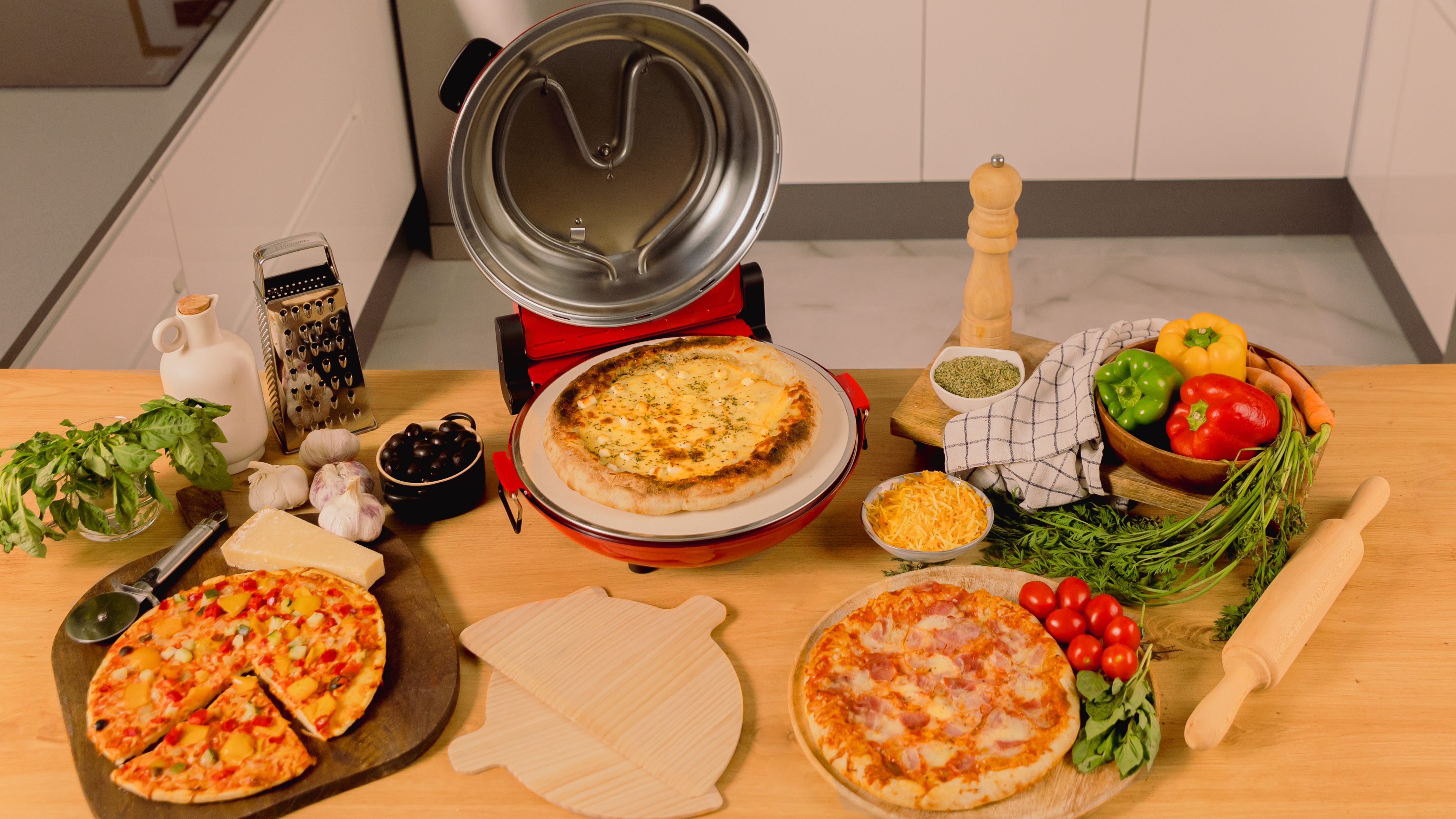 Una mesa con pizza y herramientas para hacer pizza, incluyendo un horno de pizza e ingredientes.