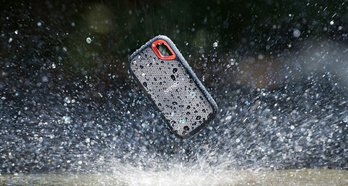 Telefon w etui jest ochlapywany wodą. Etui jest czarne i czerwone.