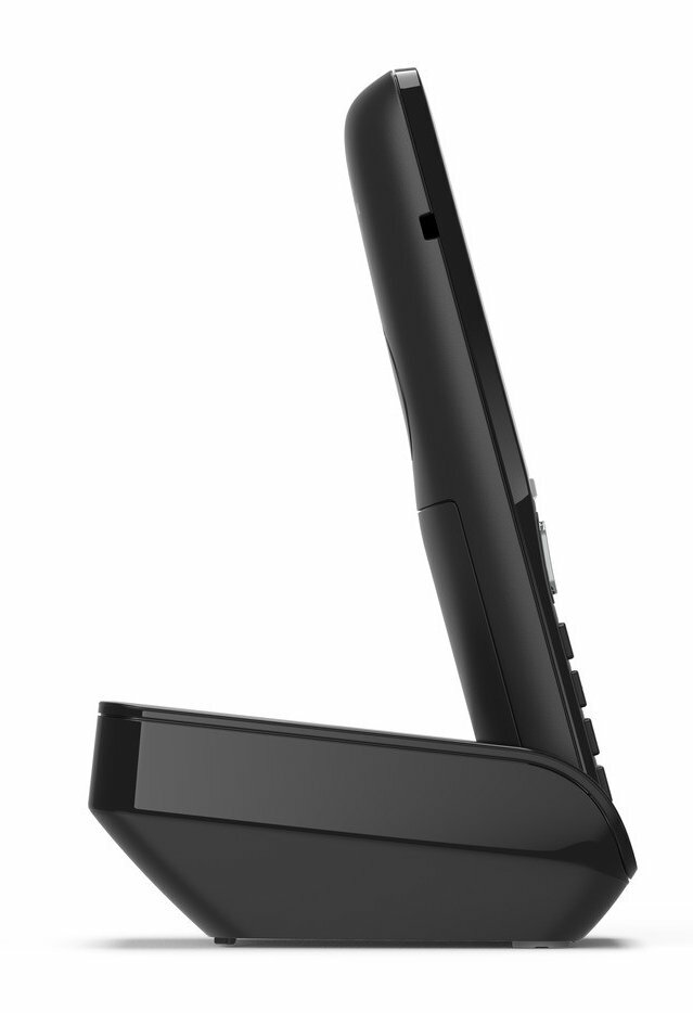 Widok z boku czarnego telefonu bezprzewodowego i podstawy. Telefon jest ustawiony pod kątem, na białym tle.