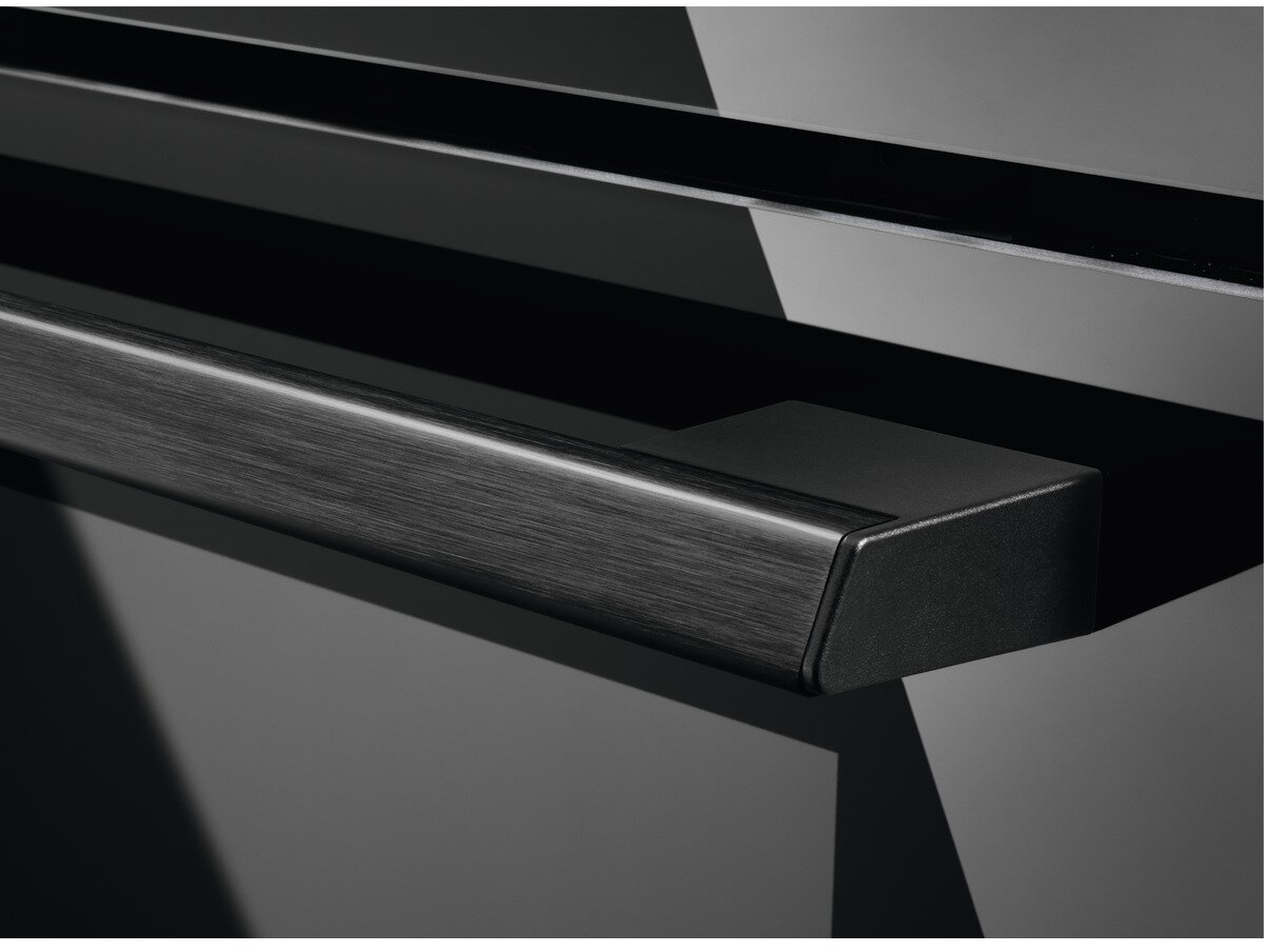 Czarny uchwyt piekarnika, zbliżenie. Błyszcząca, ciemna i odbijająca światło powierzchnia.