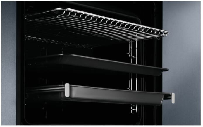 Wnętrze piekarnika. Pokazuje ruszty i tace. Wnętrze jest ciemne.