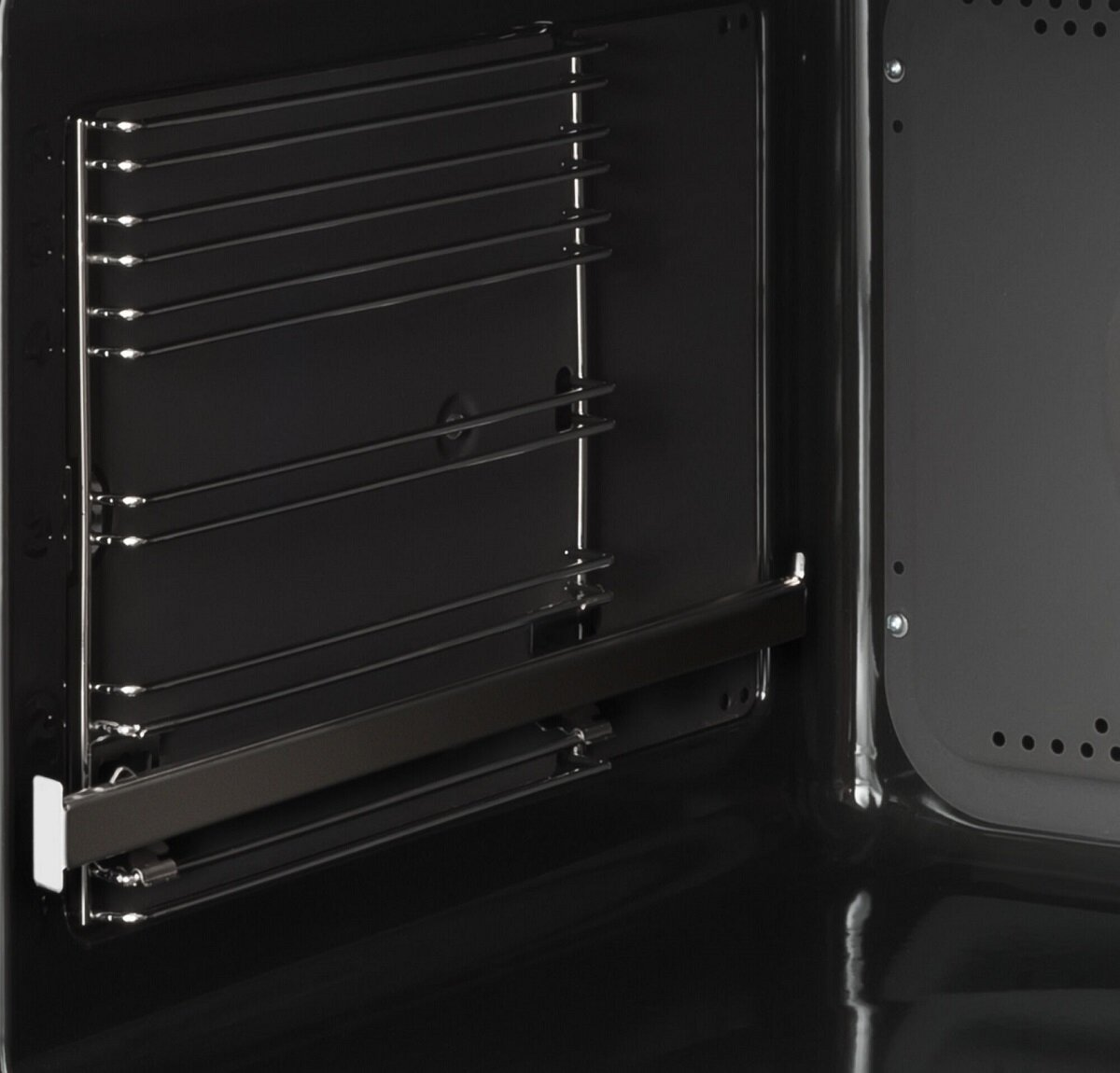 Wnętrze czarnego piekarnika. W środku znajdują się ruszty i ciemne wnętrze.