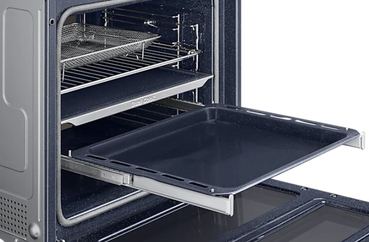 Wnętrze piekarnika z tacami. Jedna taca jest wysunięta. Powyżej znajduje się ruszt.