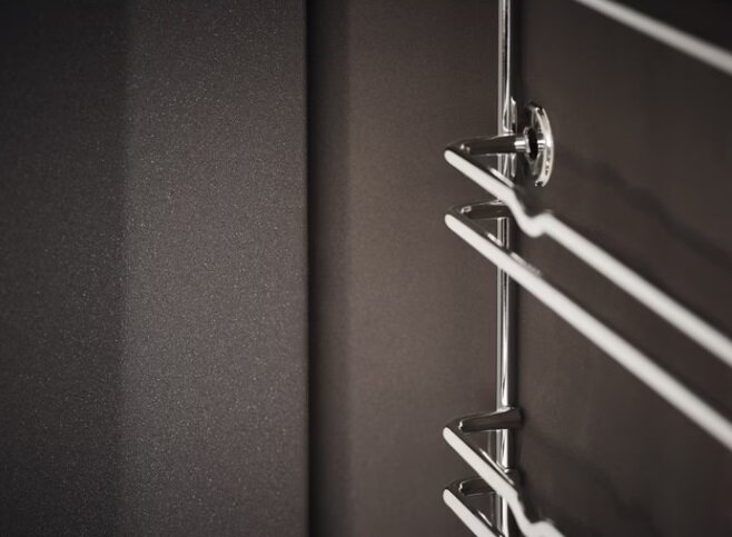 Zbliżenie nowoczesnego podgrzewacza ręczników na ciemnej ścianie.