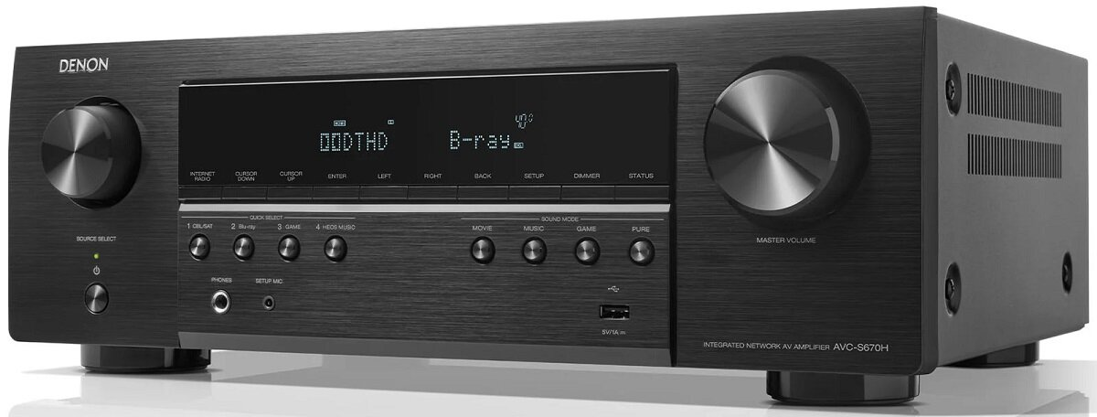 Czarny amplituner AV Denon z przyciskami, wyświetlaczem i pokrętłami. Stoi na białej powierzchni.