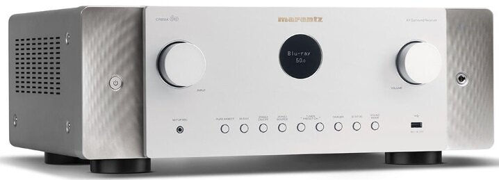 Srebrno-biały odbiornik Marantz z różnymi przyciskami i wyświetlaczem, białe tło.