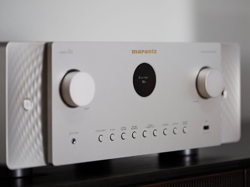 Srebrny odbiornik audio Marantz. Ma pokrętła i wyświetlacz. Marka jest widoczna.