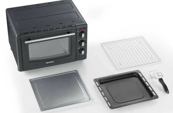 Czarny piekarnik z akcesoriami: druciana półka, taca i blacha do pieczenia. Piekarnik stoi na białej powierzchni.