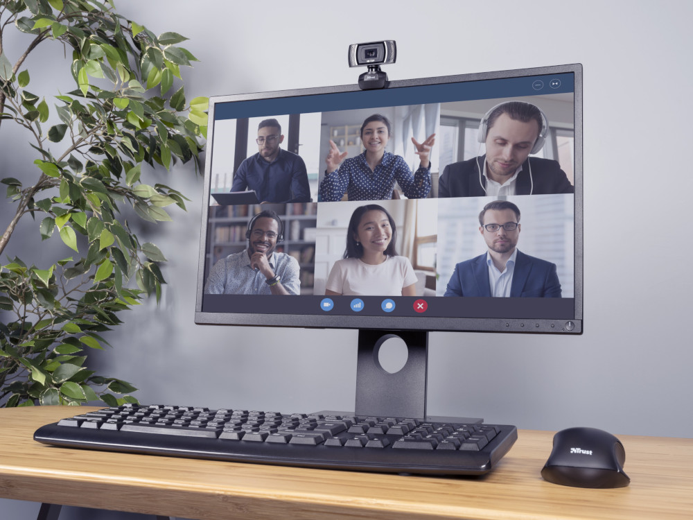 L'écran affiche un appel vidéo avec six personnes. Clavier et souris en face.