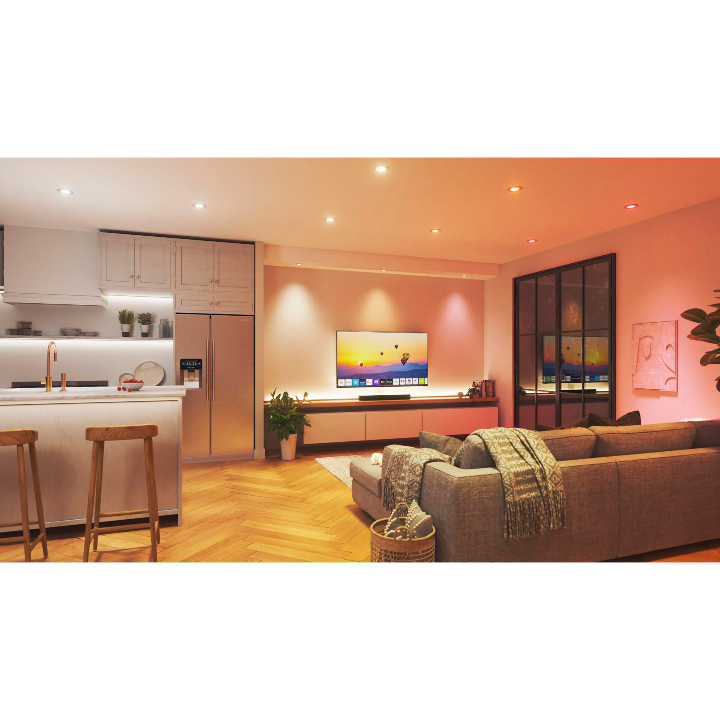 Wohnzimmer mit grauem Sofa, Fernseher auf einem Schrank und Einbaustrahlern. Warme, einladende Atmosphäre.