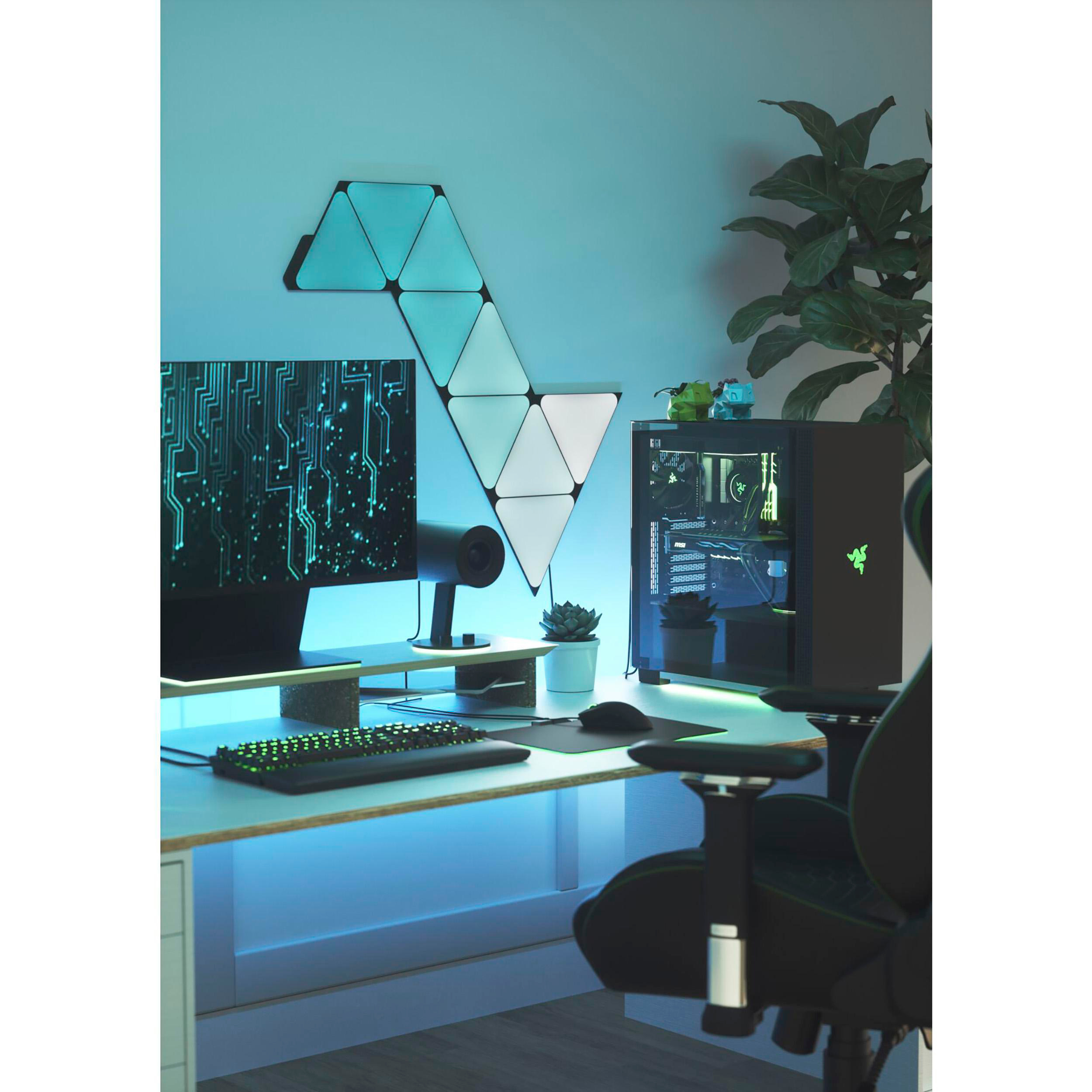 Gaming-Setup mit Monitor, PC, Schreibtisch und Lichtern. Wand mit Dreiecksleuchten.