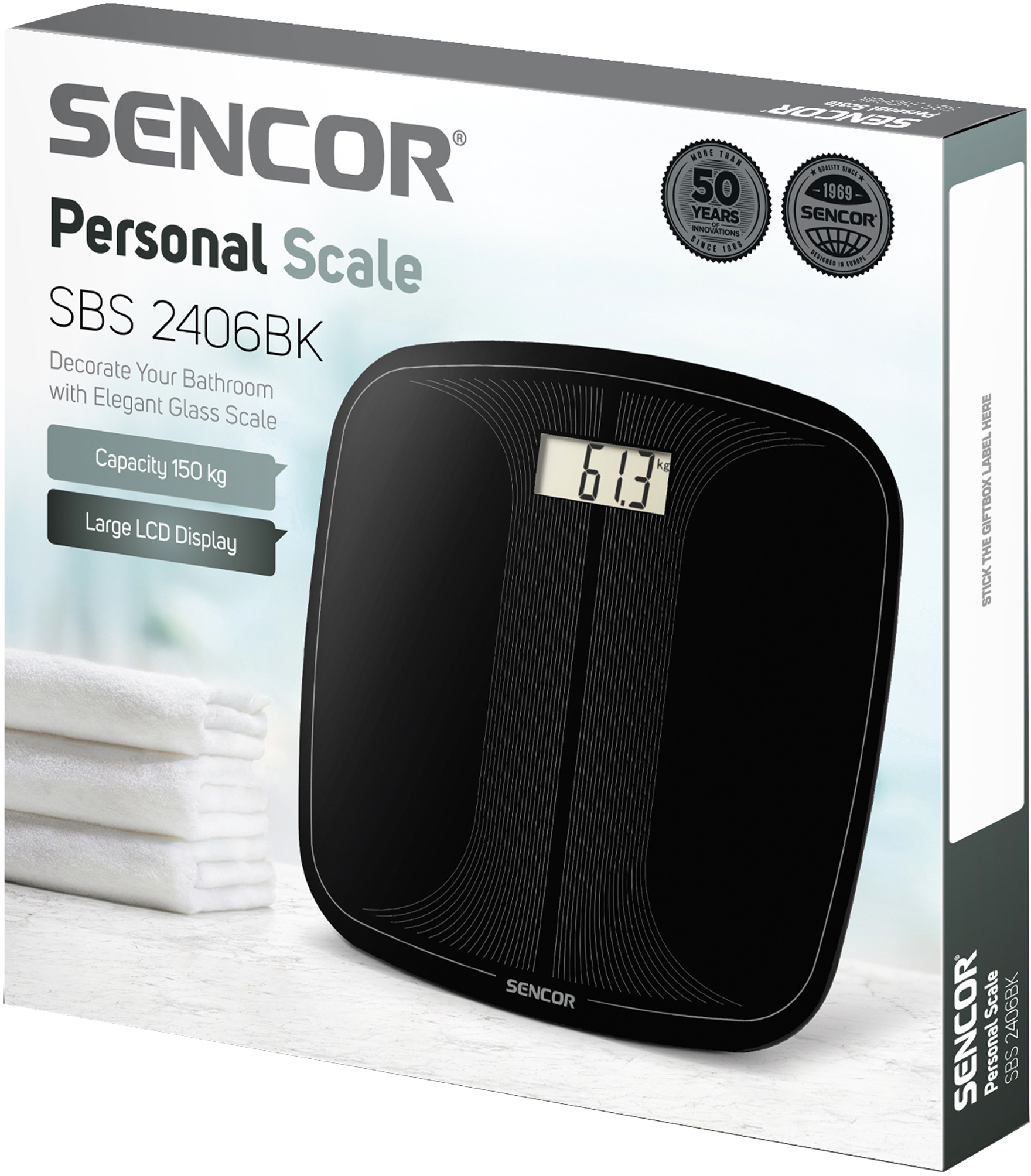 Fekete Sencor személyi mérleg 61,3 kg-ot mutat. A doboz és fehér törölközők a háttérben.