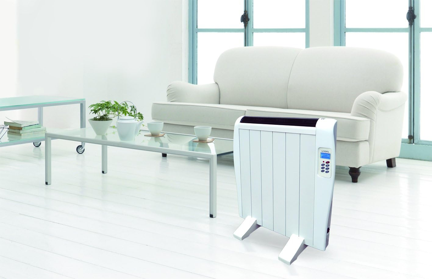 Calentador eléctrico blanco en habitación blanca. Sofá, mesa y plantas blancas también.