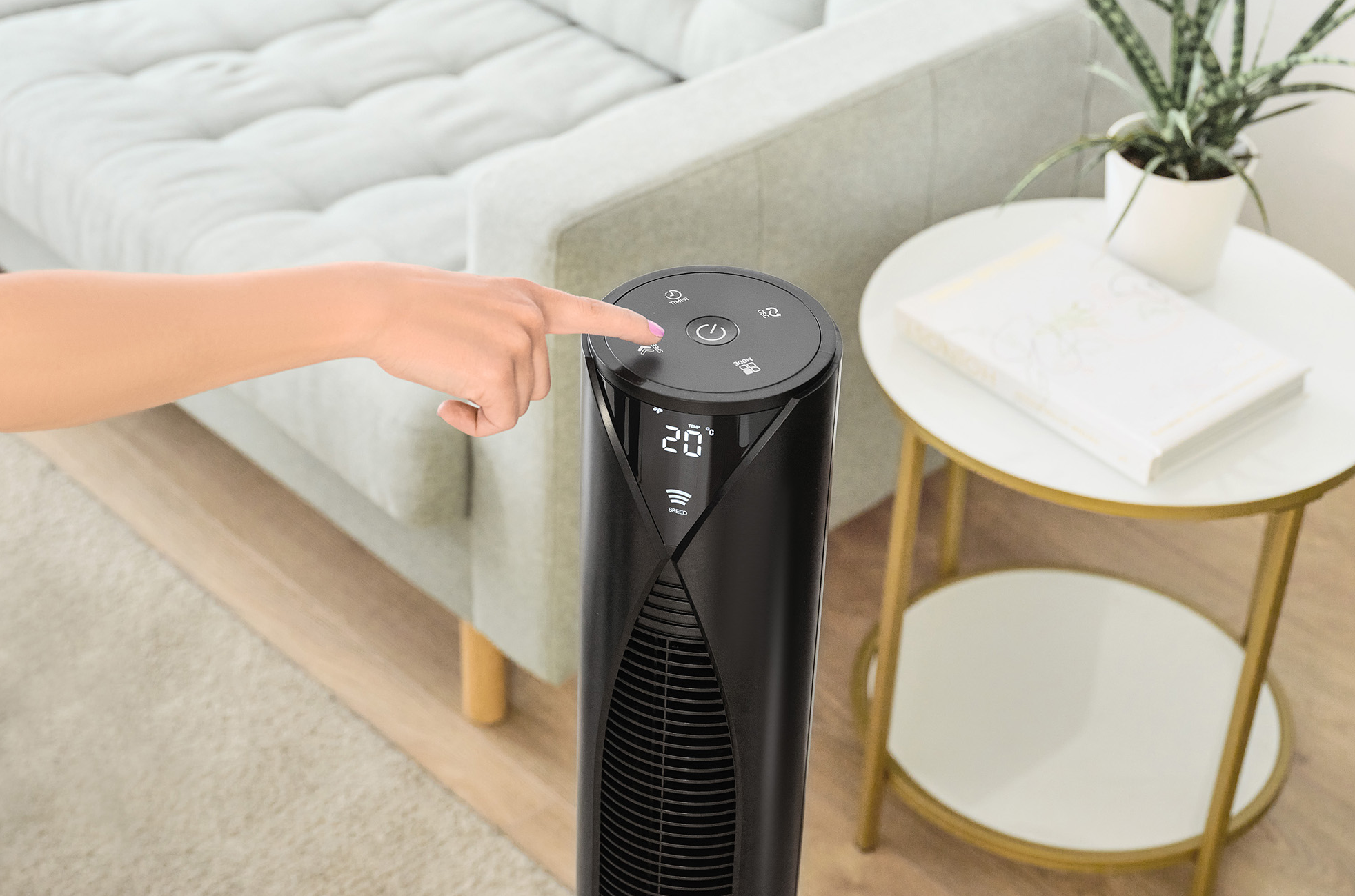 Egy személy keze megnyom egy gombot egy fekete ventilátoron.