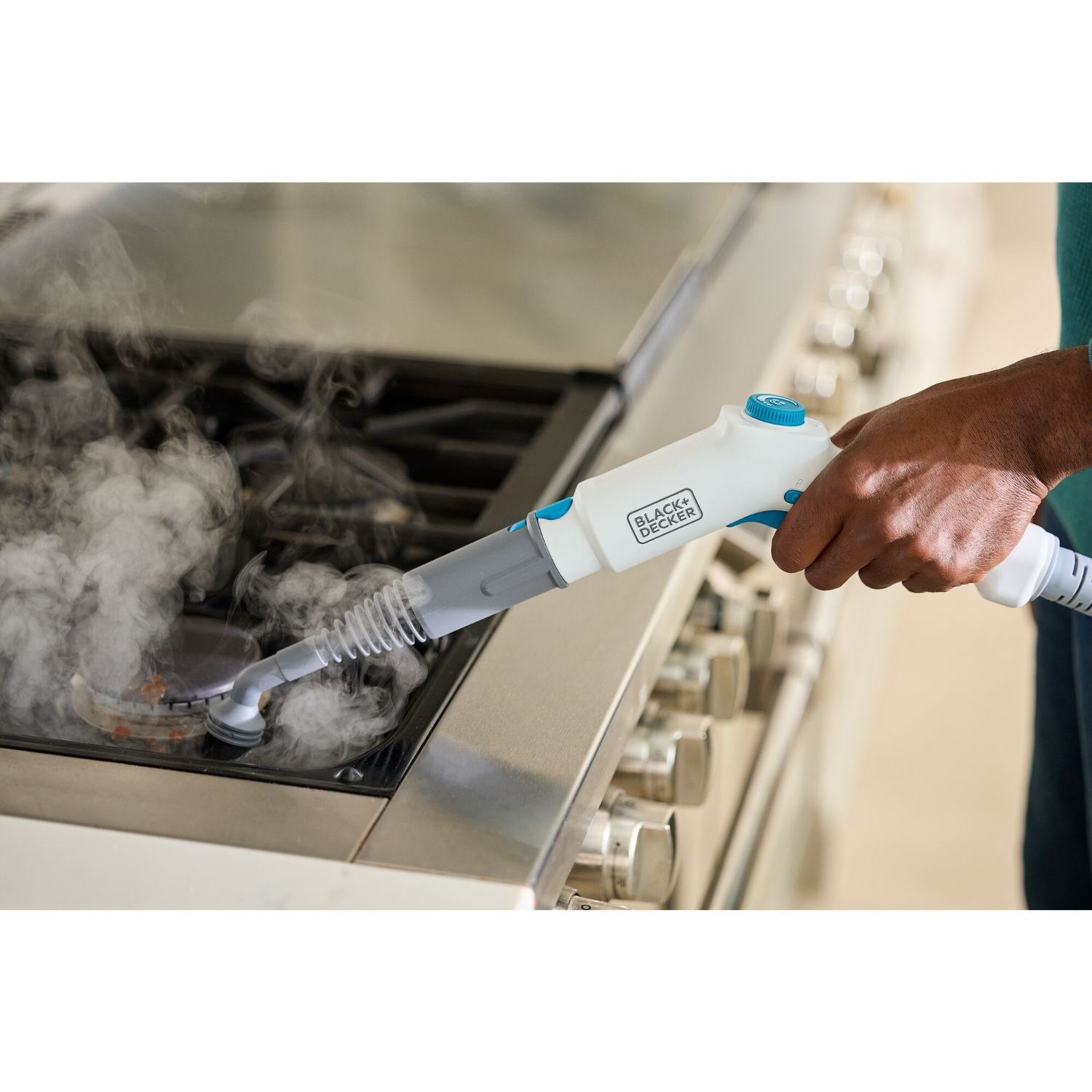 A person cleaning a stove with a steam cleaner.