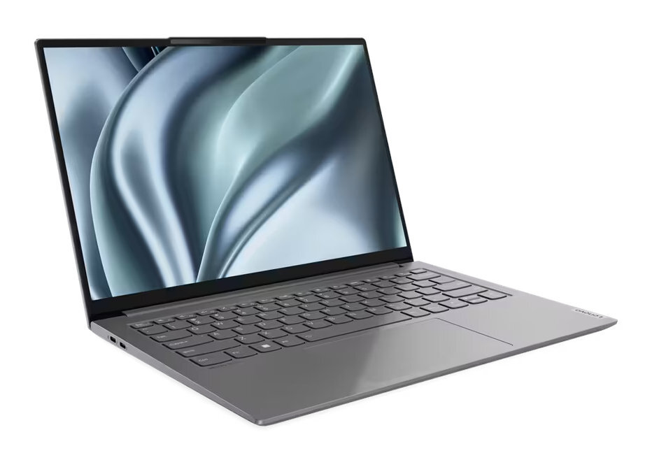 Szary laptop na białej powierzchni. Ekran pokazuje faliste, abstrakcyjne tło. Widoczne jest logo Lenovo.