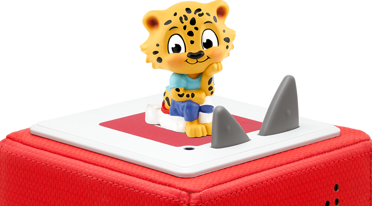 Ein Spielzeugleopard sitzt auf einer roten Box, zwei Haifischflossen sind sichtbar.